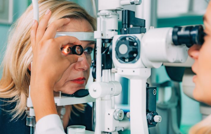 An optometrist performs an eye exam on a patient using a slit lamp. Examing for vitreous floaters.