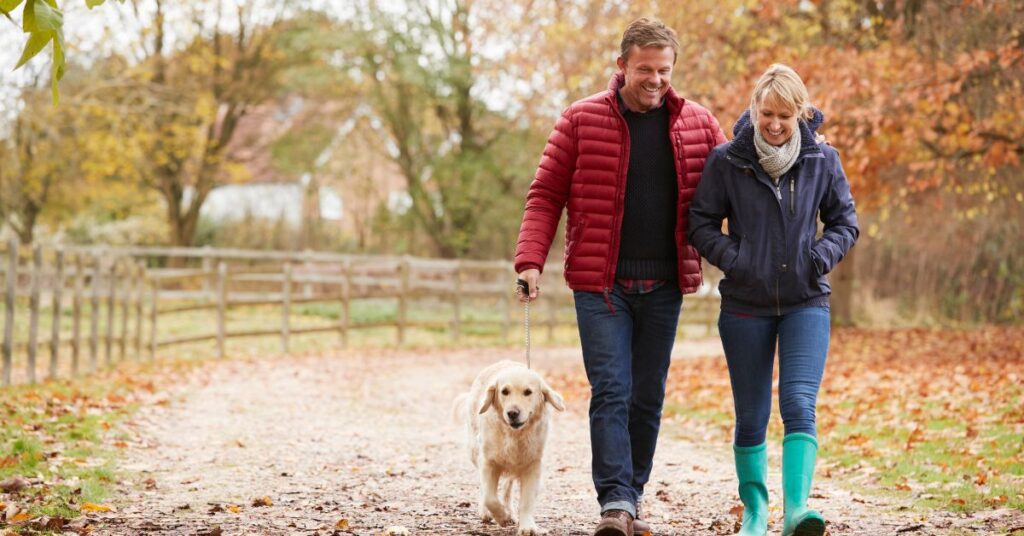 A man and woman enjoy a sunny stroll, walking their dog while chatting about their favorite products like Blephasol Duo.