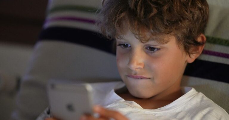 A young child looking at a tphone screen at close range.