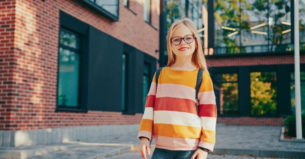 A young child smiling while wearing myopia control glasses