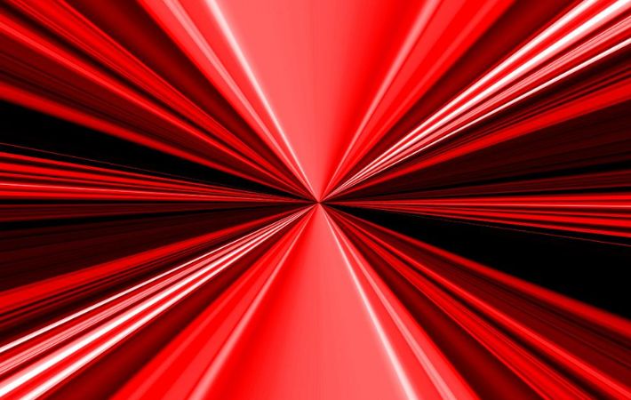 Abstract image featuring sharp red and white lines radiating from a central point, creating a dynamic, starburst or tunnel effect against a black background.