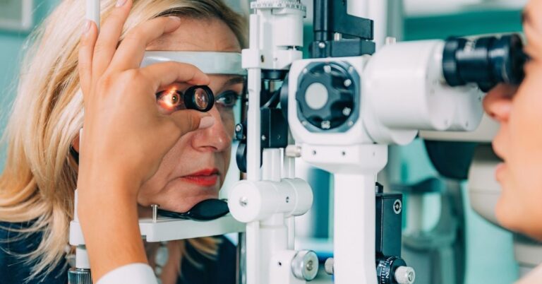 A woman undergoes an eye examination using a slit lamp, with an optometrist shining a light into her eye to check for potential issues.
